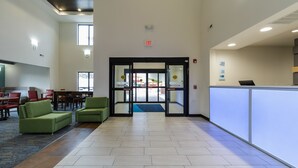 A lobby with a reception desk, a blue carpet, and green chairs. - Holiday Inn Express Hotel & Suites South Bend by IHG (South Bend)