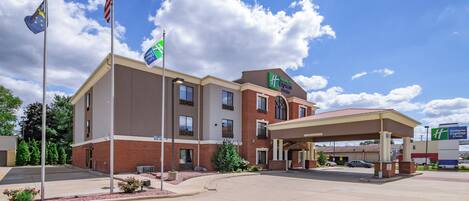 Un hotel Holiday Inn Express bajo un cielo despejado con nubes.