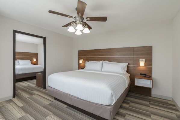 A hotel room with a large bed, a ceiling fan, bedside lamps, and a mirror.