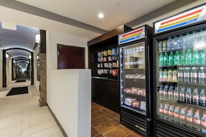 Pasillo de hotel con área de máquinas expendedoras, incluyendo botellas de Sprite y Coca-Cola.
