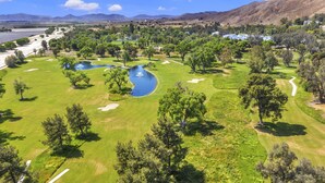A golf course with a pond, trees, and a mountainous backdrop. - Hampton Inn And Suites Hemet (Hemet)