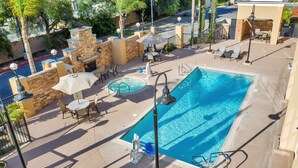 A rooftop pool area with a hot tub, lounge chairs, and a stone wall. - Hampton Inn And Suites Hemet (Hemet)