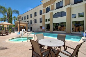 Uma área junto à piscina, com espreguiçadeiras e uma mesa.