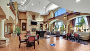 A spacious lobby with a stone fireplace, seating areas, and large windows offering views. - Hampton Inn And Suites Hemet (Hemet)
