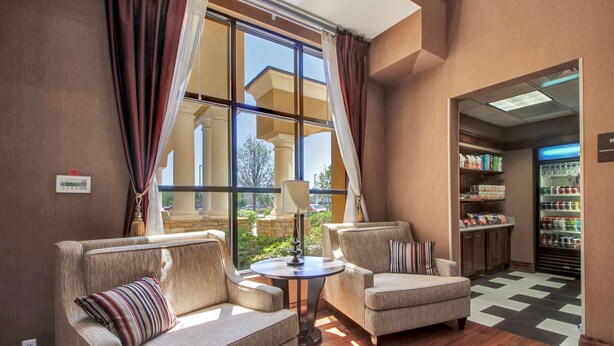 A hotel lobby with a checkered floor, two sofas, a small table, and a refrigerator stocked with beverages. - Hampton Inn And Suites Hemet (Hemet)