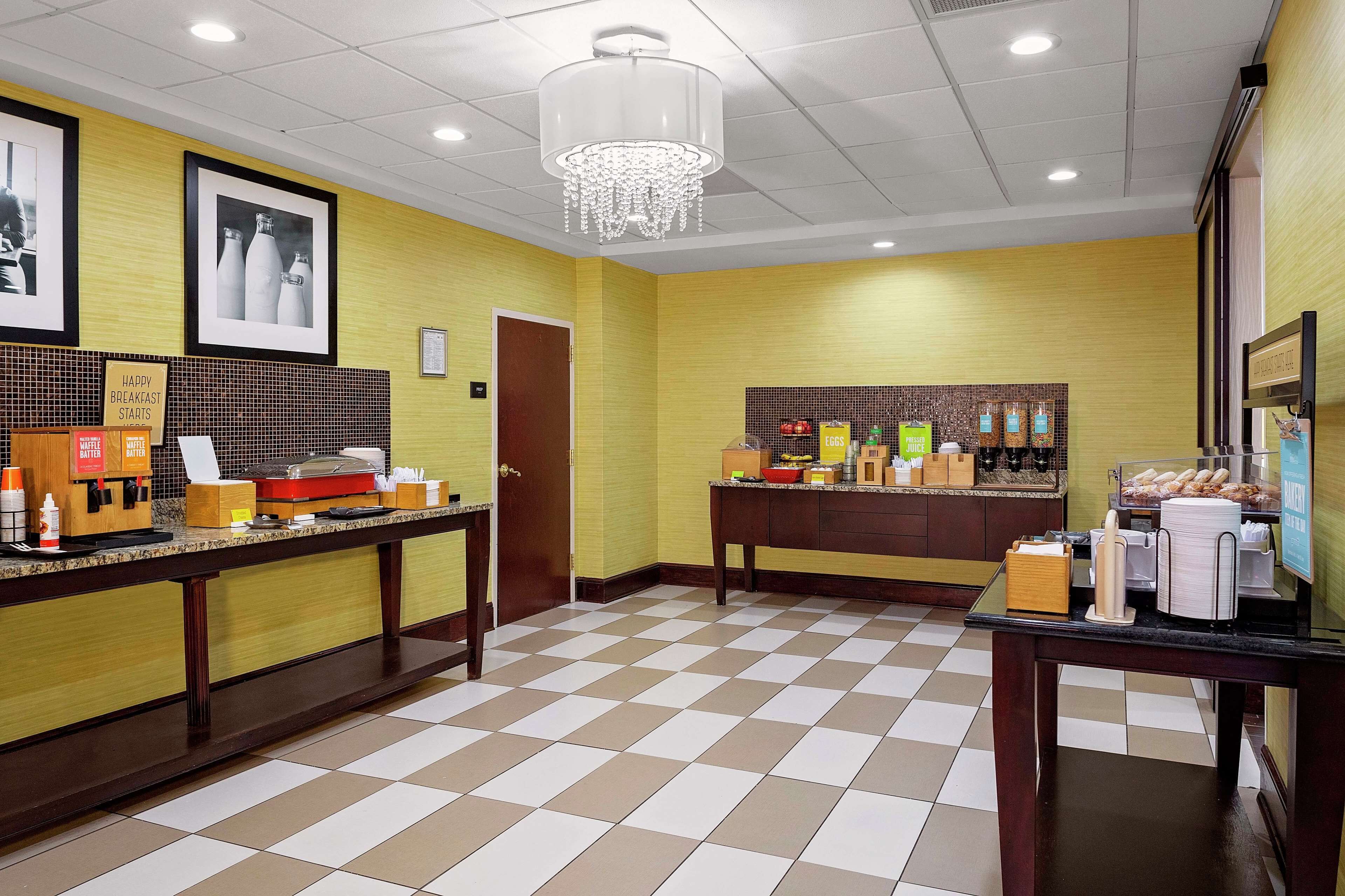 A hotel lobby with a checkered floor, a reception desk, and a wall with framed pictures and a chandelier.
