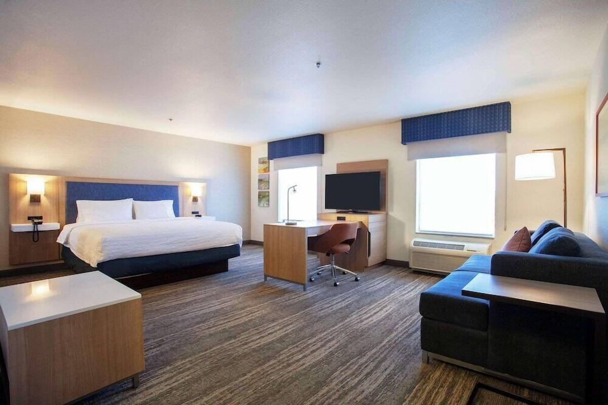 Ein Hotelzimmer mit Bett, Schreibtisch, Stuhl und einer Couch.
