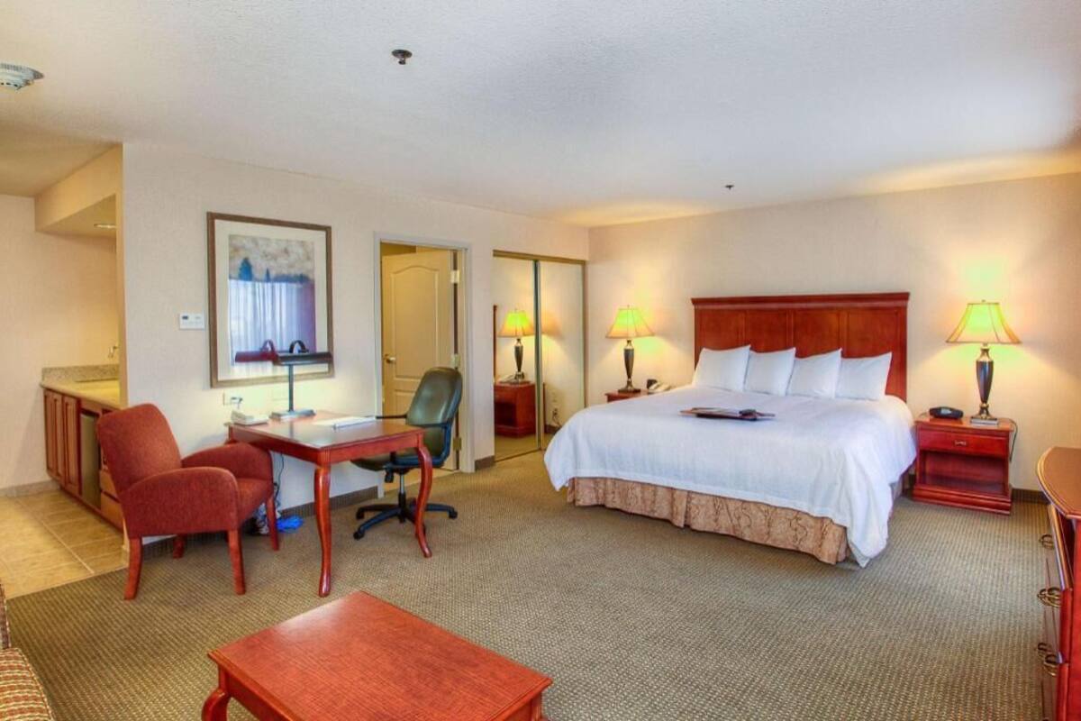 Ein Hotelzimmer mit Bett, Schreibtisch, Stuhl und Lampen.