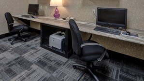 Une salle de conférence équipée de deux bureaux, chacun comprenant un ordinateur, une lampe et un téléphone. Une imprimante se trouve sous l’un des bureaux.