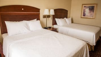 Habitación de hotel con dos camas, una mesita de noche con lámparas y un cuadro enmarcado en la pared.