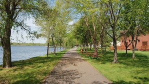 A park with a paved walkway, benches, and picnic tables along a lakeside path.
