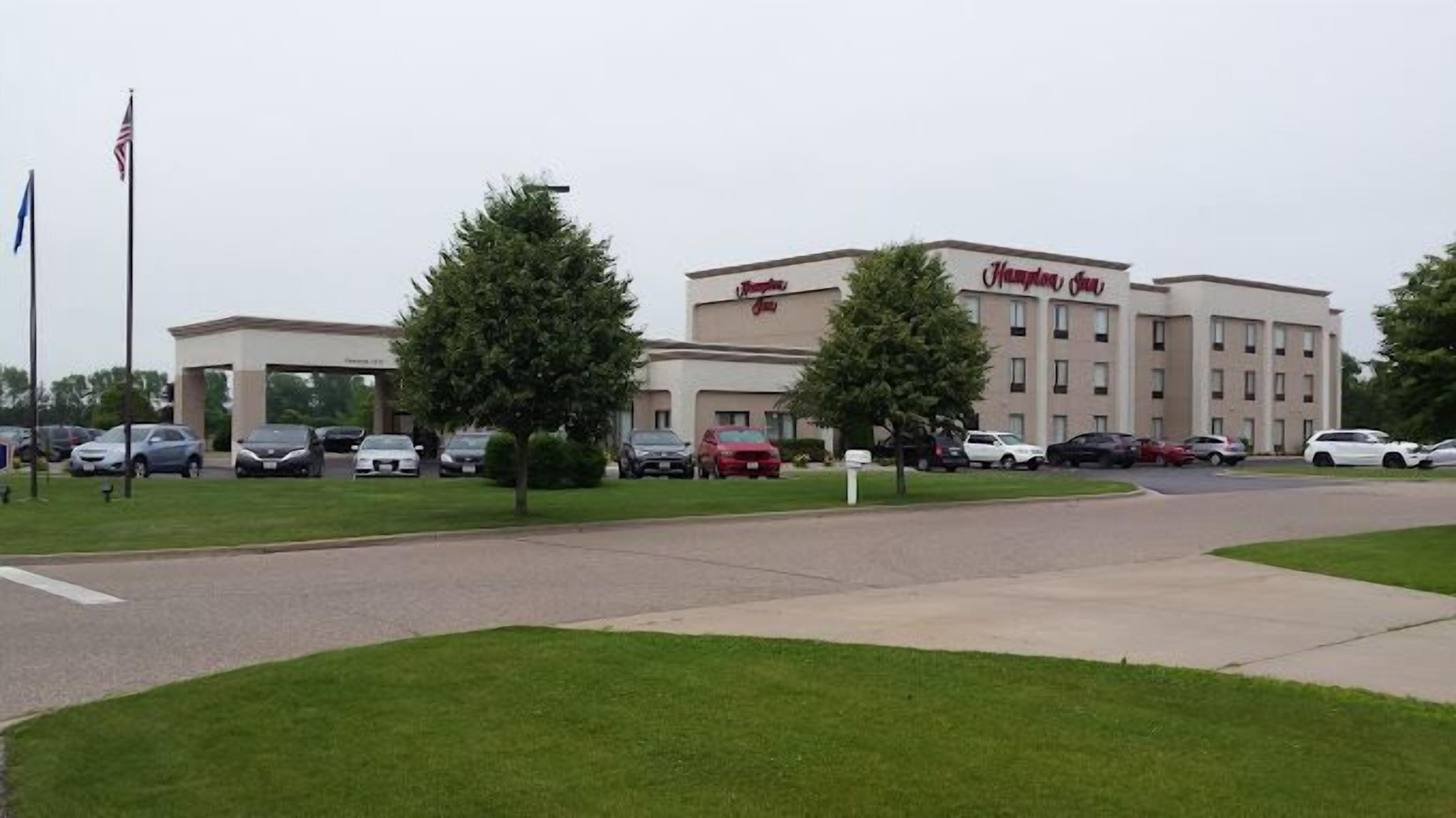 A Hampton Inn hotel with a parking lot and a grassy area in front.