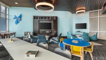 A modern room with a large flat-screen TV, comfortable seating, a round table, and a foosball table.