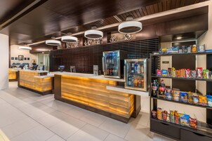 En moderne hotellobby med reception, siddeområde og snackbar.