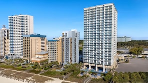 Un hotel moderno de gran altura con varios pisos, balcones y una zona de piscina.