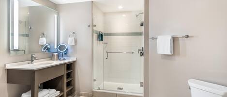 Un baño moderno con ducha de vidrio, tocador con espejo y inodoro.