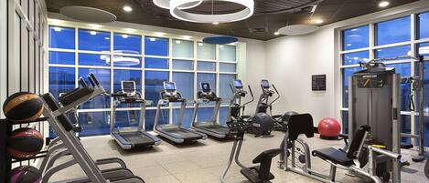 A modern gym with treadmills, elliptical machines, and free weights.