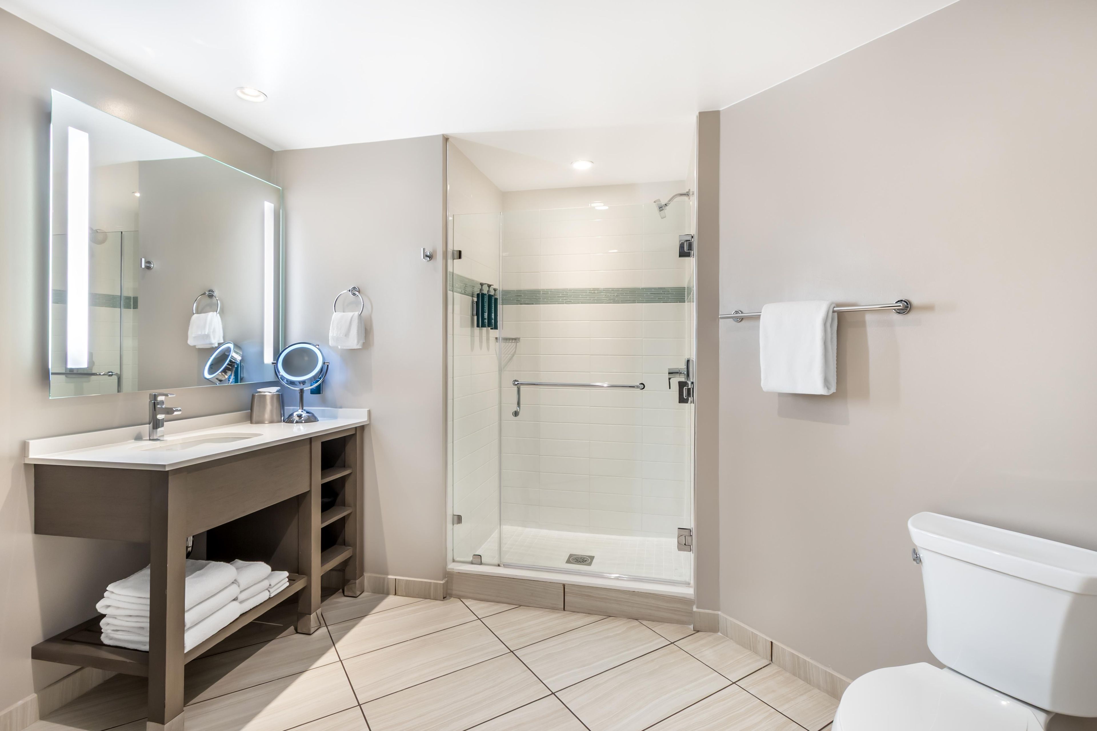 Een moderne badkamer met een douchecabine van glas, een wastafel met spiegel en een toilet.