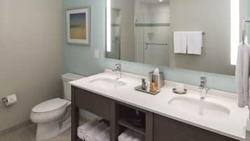 A modern bathroom with two sinks, a toilet, a shower, and a large mirror.