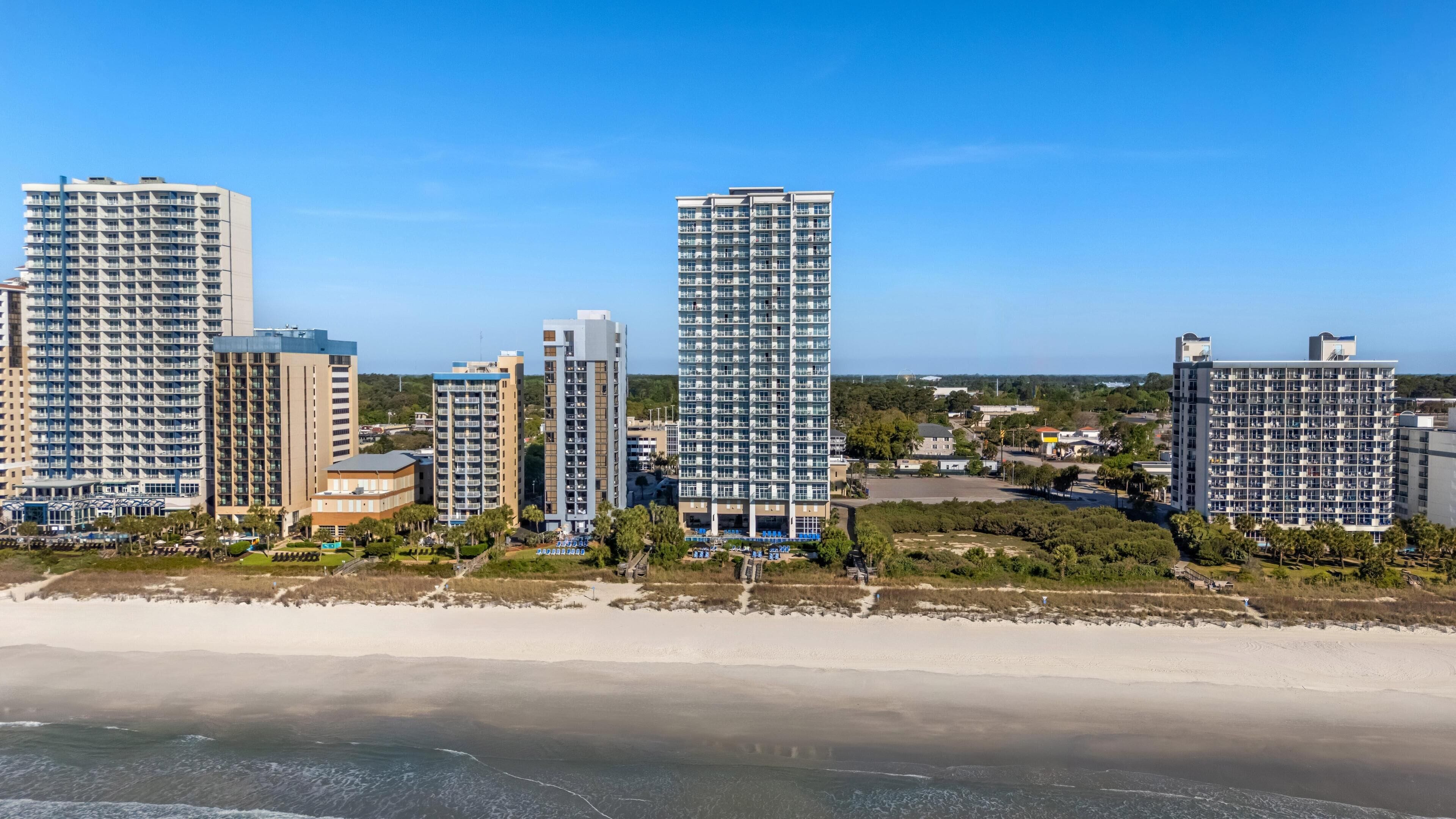 Een kuststadsgezicht met hoge gebouwen, een strand en heldere lucht.