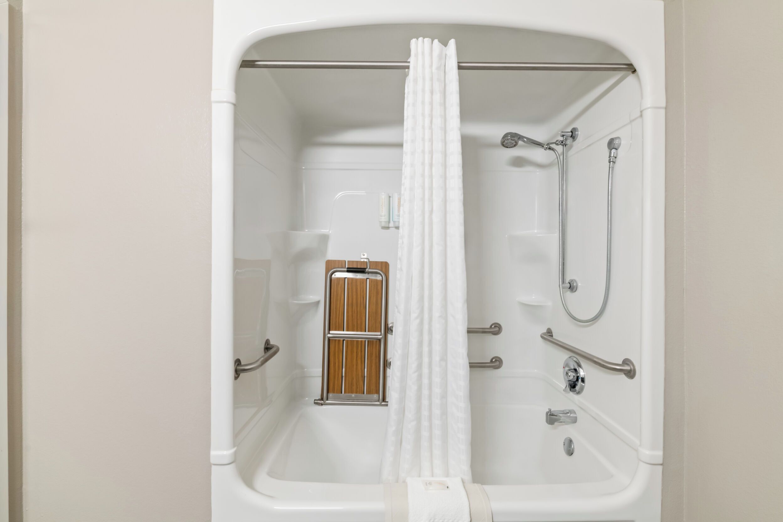Een badkamer met een bad, douche en handgrepen.