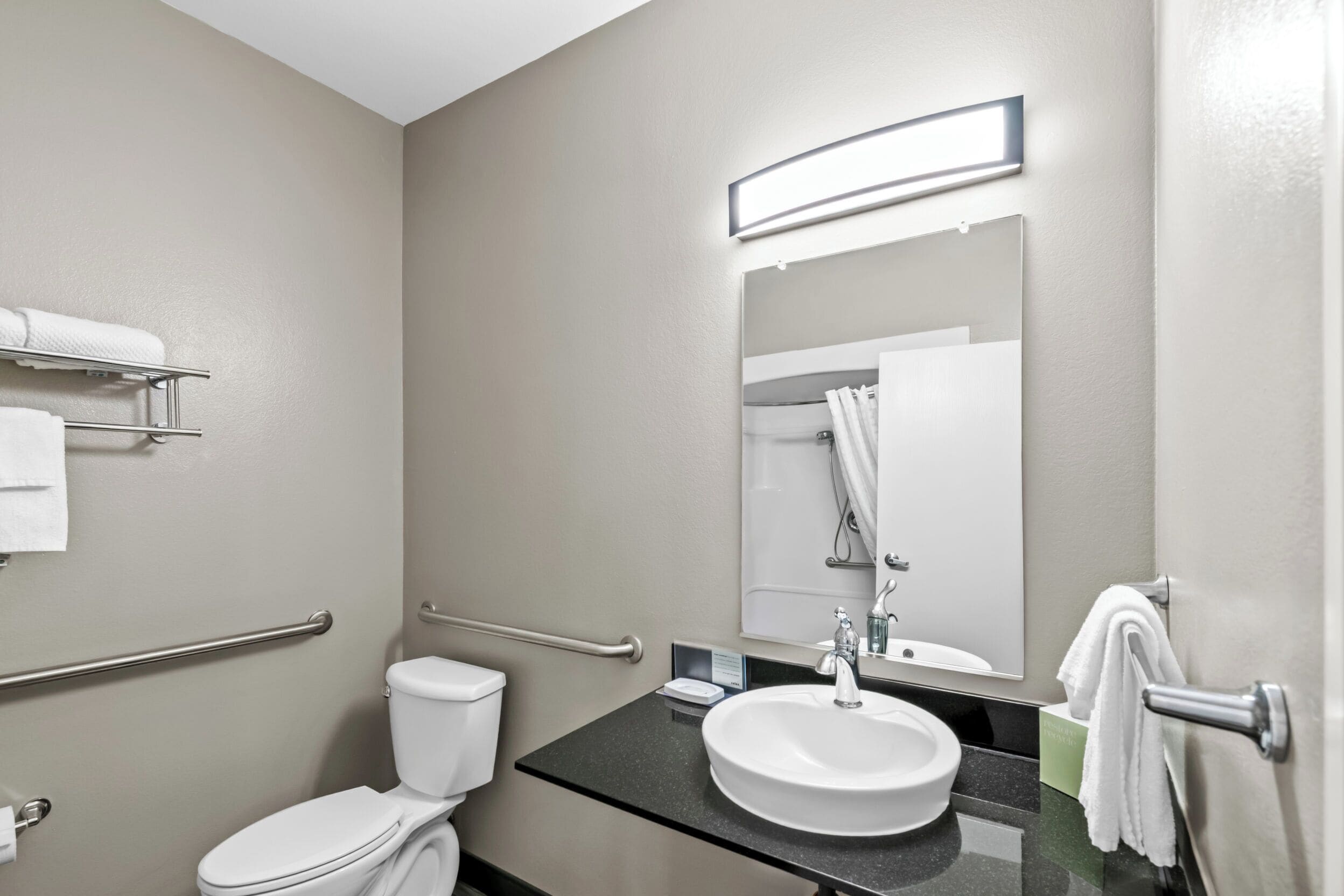 A modern bathroom with a toilet, sink, and mirror.