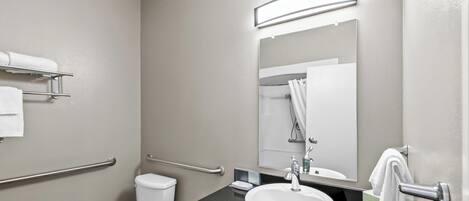 A modern bathroom with a toilet, sink, and mirror.