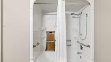 A bathroom with a bathtub, shower, and grab bars.