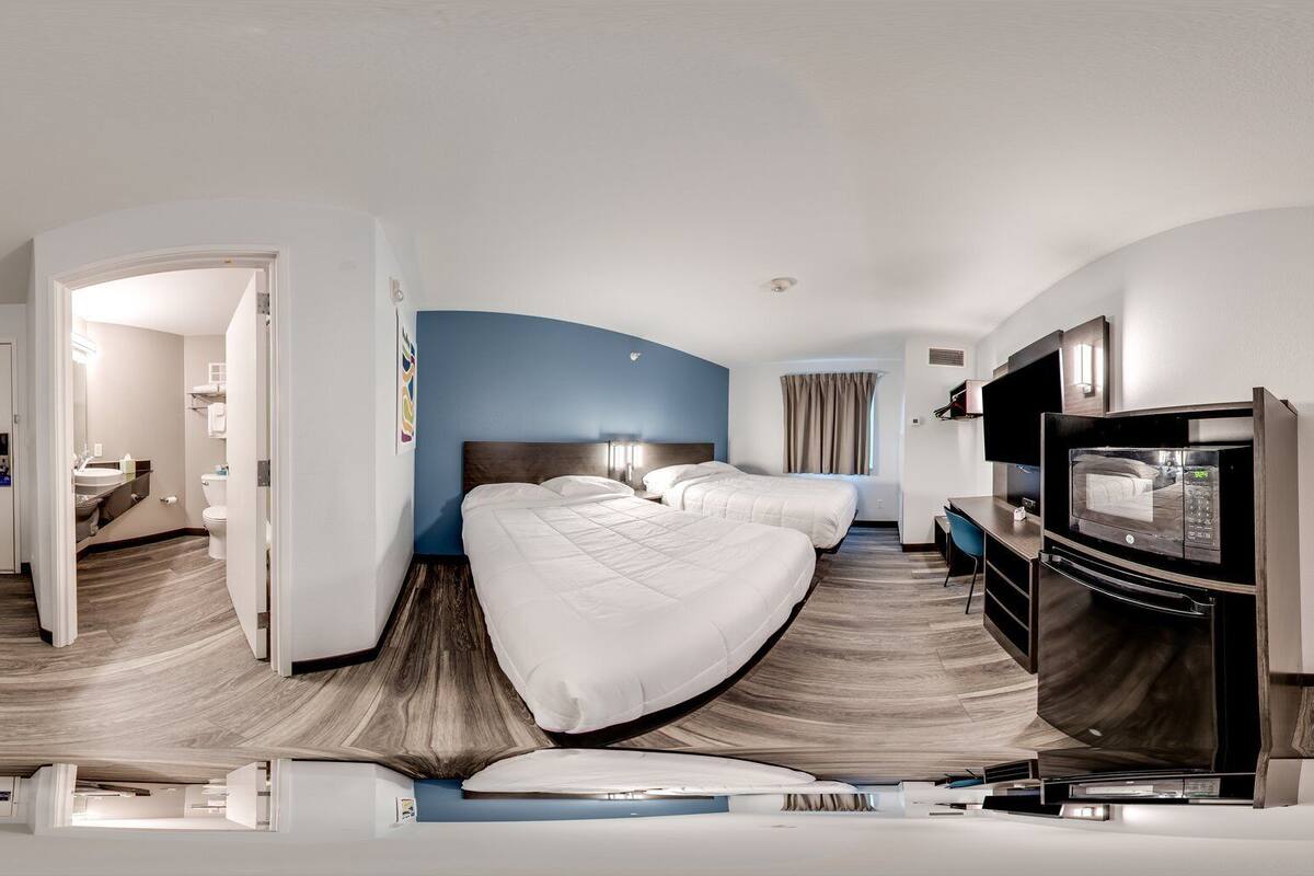 A hotel room with two beds, a TV, and a desk.