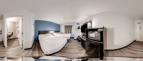 Una habitación de hotel con dos camas, televisión y escritorio.