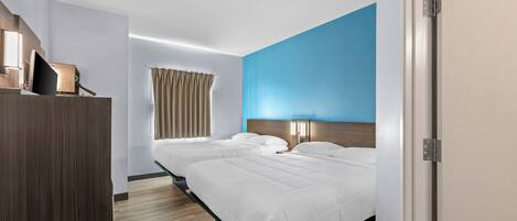Une chambre d’hôtel avec deux lits, une armoire en bois, un mur d’accent bleu et une fenêtre avec des rideaux.