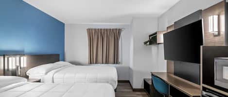 Een hotelkamer met twee bedden, een bureau, een televisie en een raam met gordijnen.