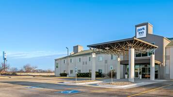 A Park Inn hotel with a covered entrance, a parking lot, and a clear blue sky.