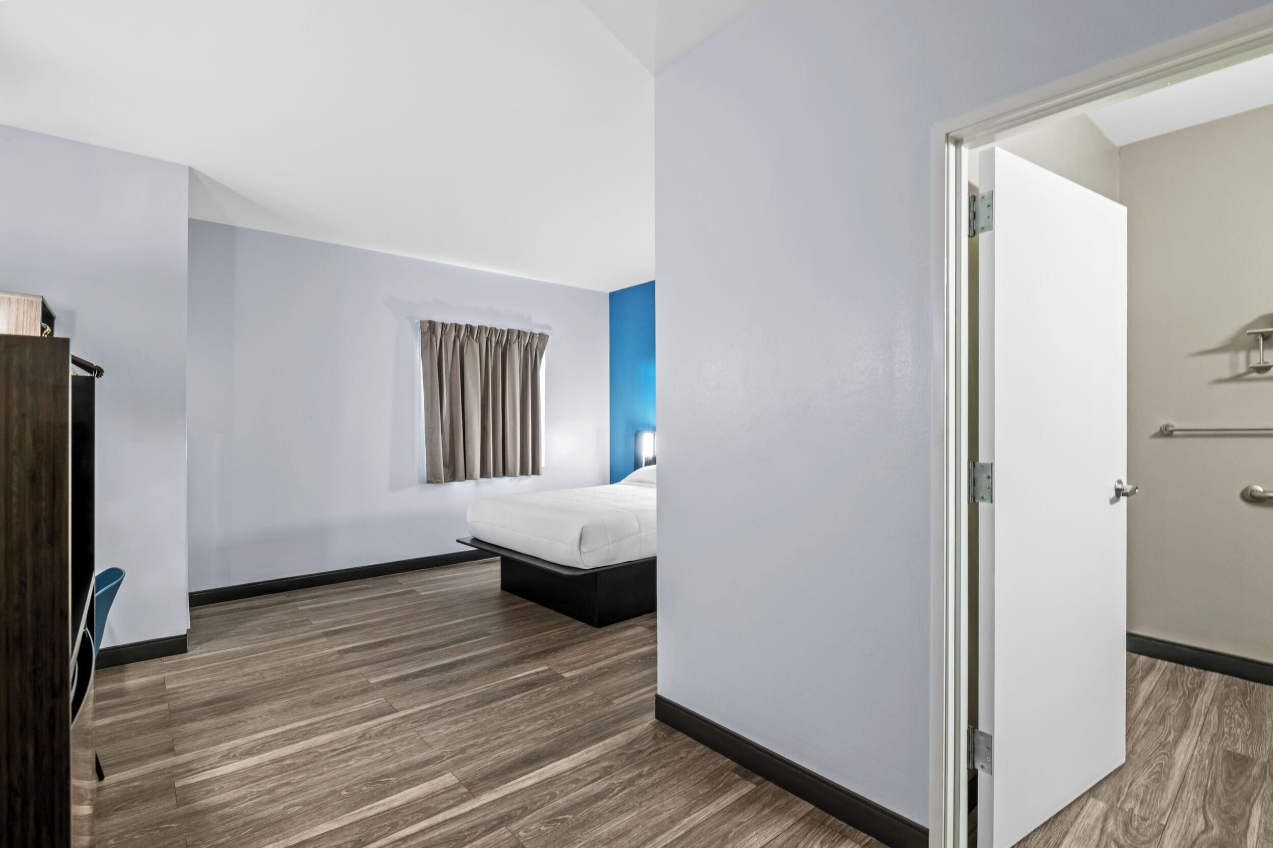 Een hotelkamer met een bed, een kledingkast en een raam met gordijnen.