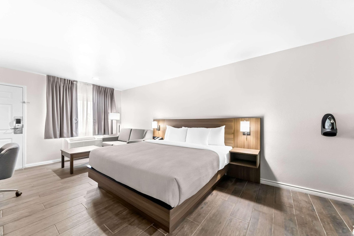 A hotel room with a large bed, bedside tables, a desk, and a chair.