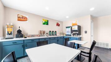 Eine moderne Küche mit weißer Arbeitsplatte, blauen Schränken und einer Kaffeestation.