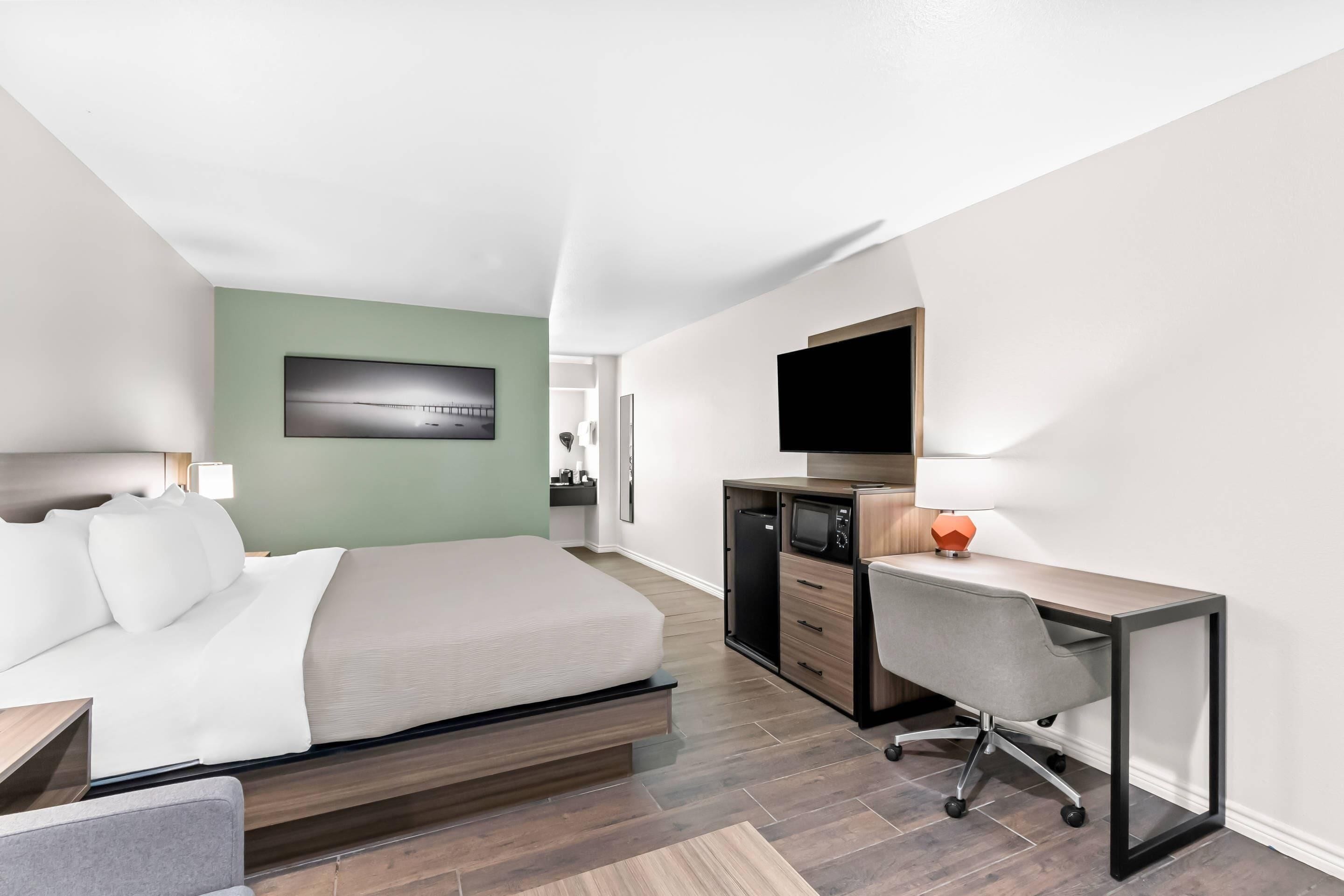 Una habitación de hotel moderna con cama, escritorio y televisor.