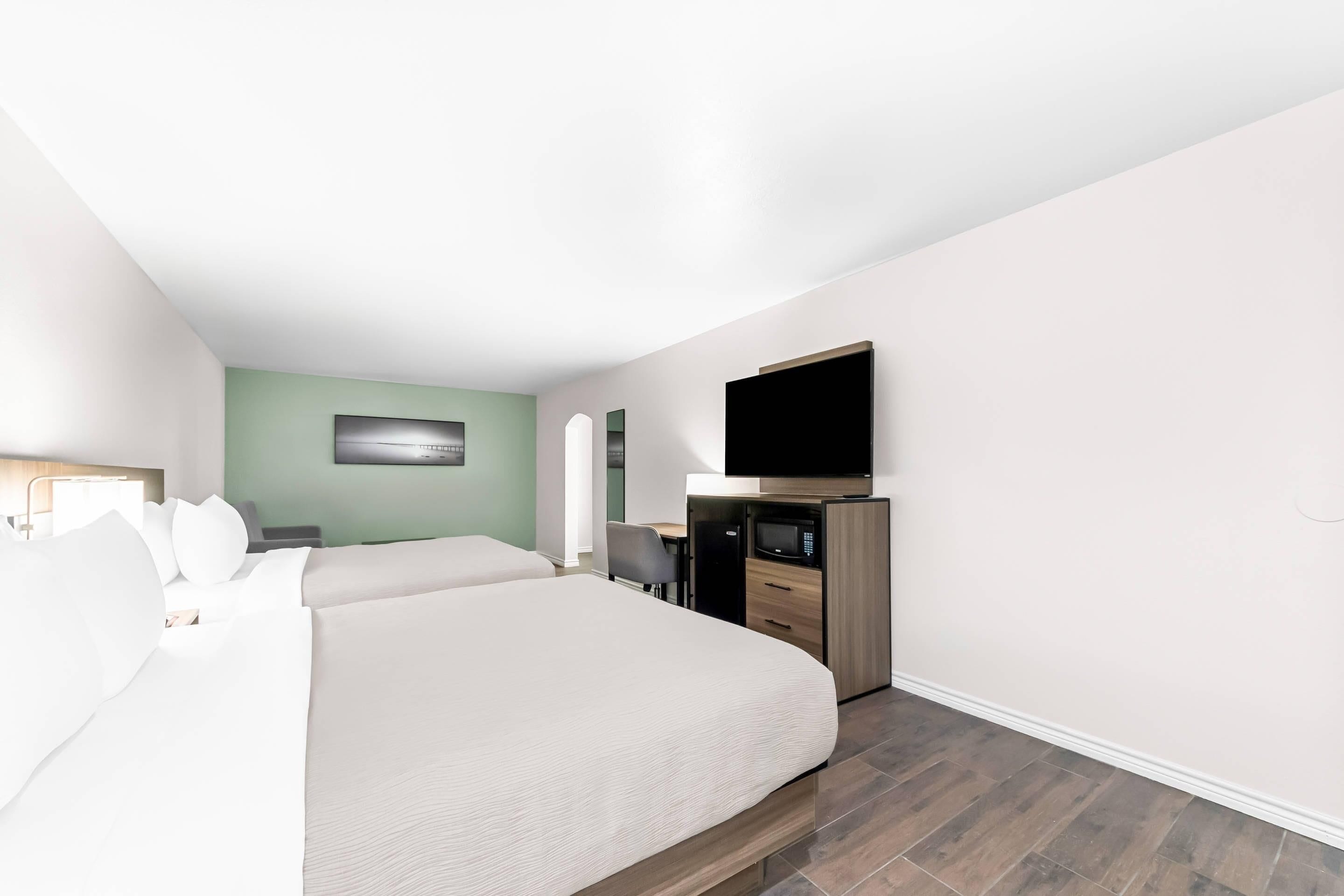 Une chambre d’hôtel dotée d’un grand lit, d’un bureau, d’une télévision à écran plat et d’un four à micro-ondes.