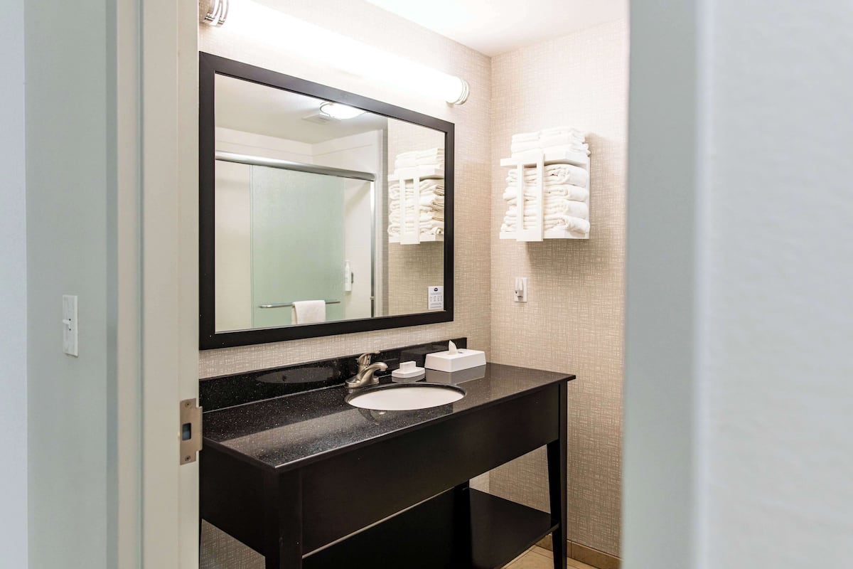 A bathroom with a black sink, a large mirror, and a towel rack with folded towels.