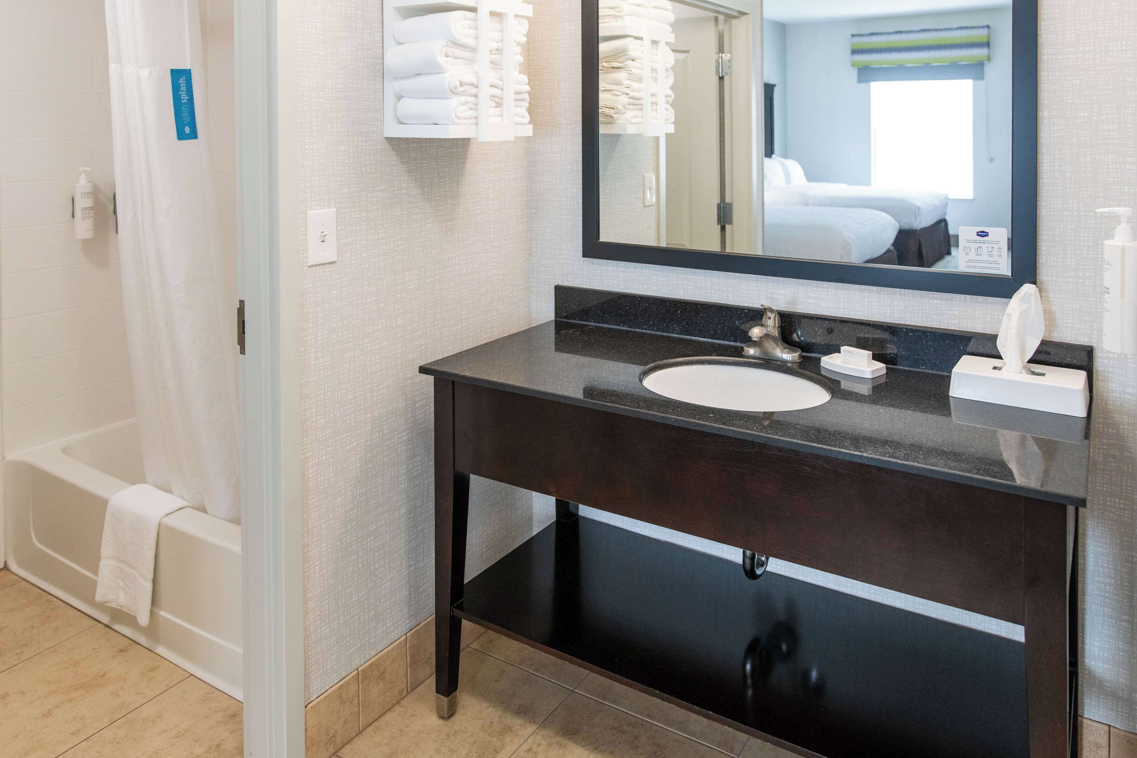 A modern bathroom with a dark wooden vanity, a white sink, and a large mirror.