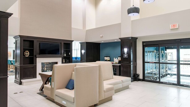A spacious lobby with a beige sectional sofa, a fireplace, and a view of the outside through large glass doors. - Hampton Inn & Suites Effingham (Effingham)