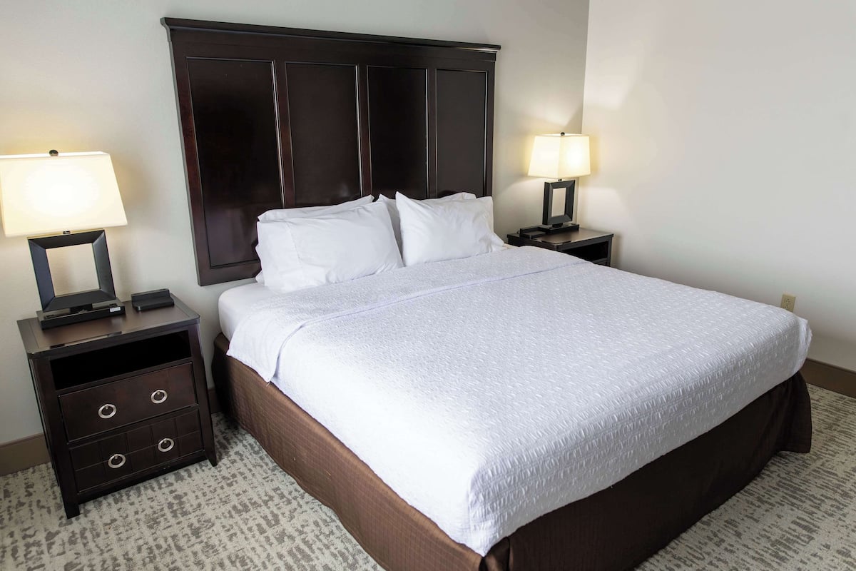 A hotel room with a large bed, two nightstands, and a dark wooden headboard.