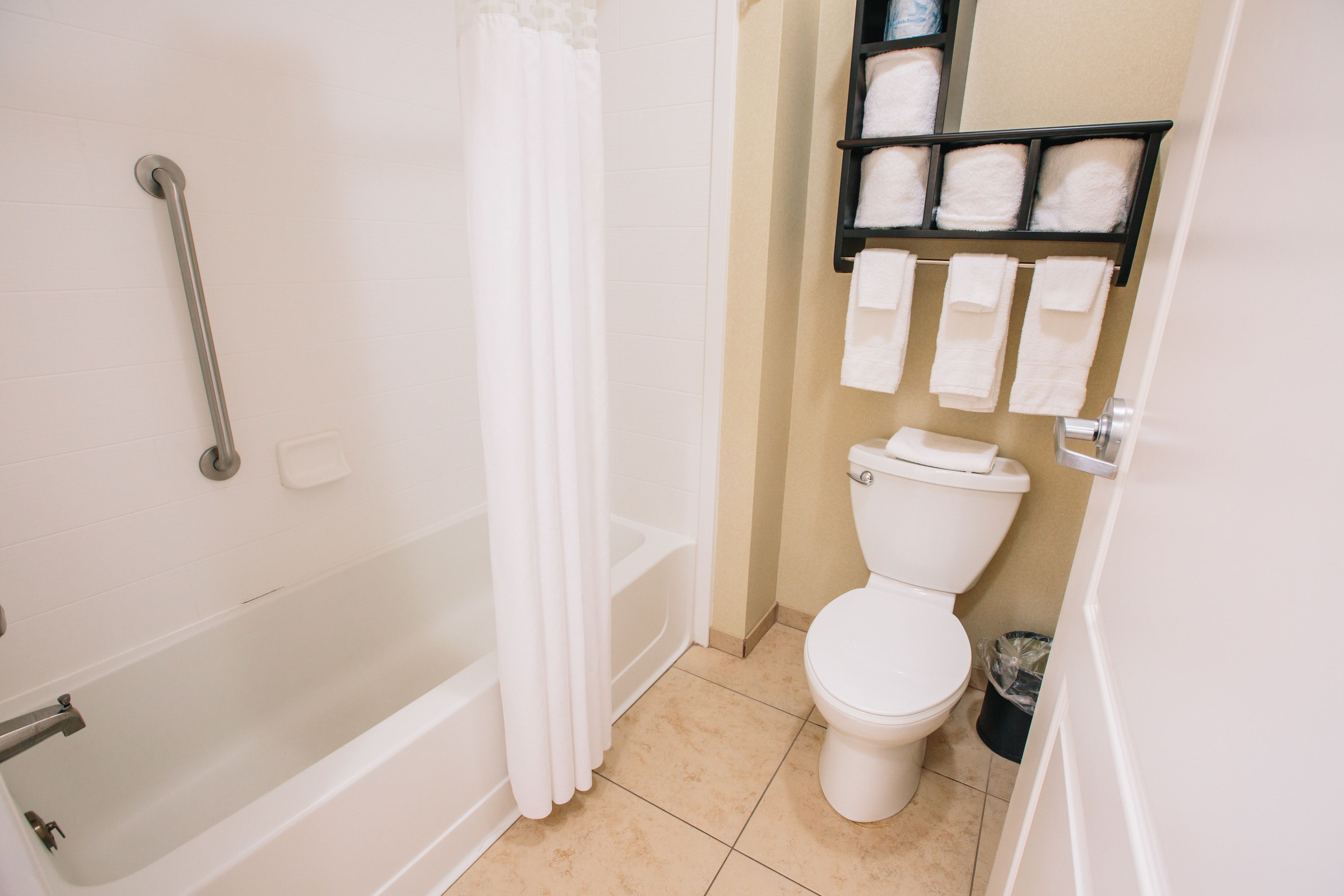 Un baño con bañera, inodoro y un estante con toallas.