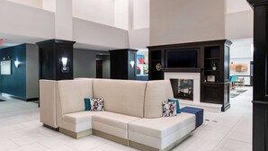 A modern living area with a sectional sofa, a fireplace, and a flat-screen TV. - Hampton Inn & Suites Effingham (Effingham)