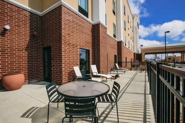 An outdoor patio with a round table and chairs, a brick wall, and a clear blue sky. - Hampton Inn & Suites Effingham (Effingham)
