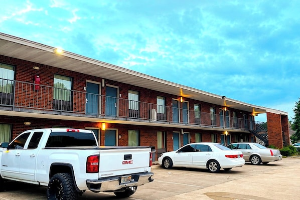 A multi-story motel with a brick facade, a covered parking area, and a staircase leading to the upper level.