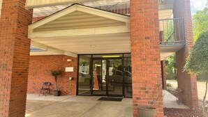 A brick building with a covered entrance, glass doors, and a small outdoor seating area. - Delta Inn West Helena US 49 AR (West Helena)