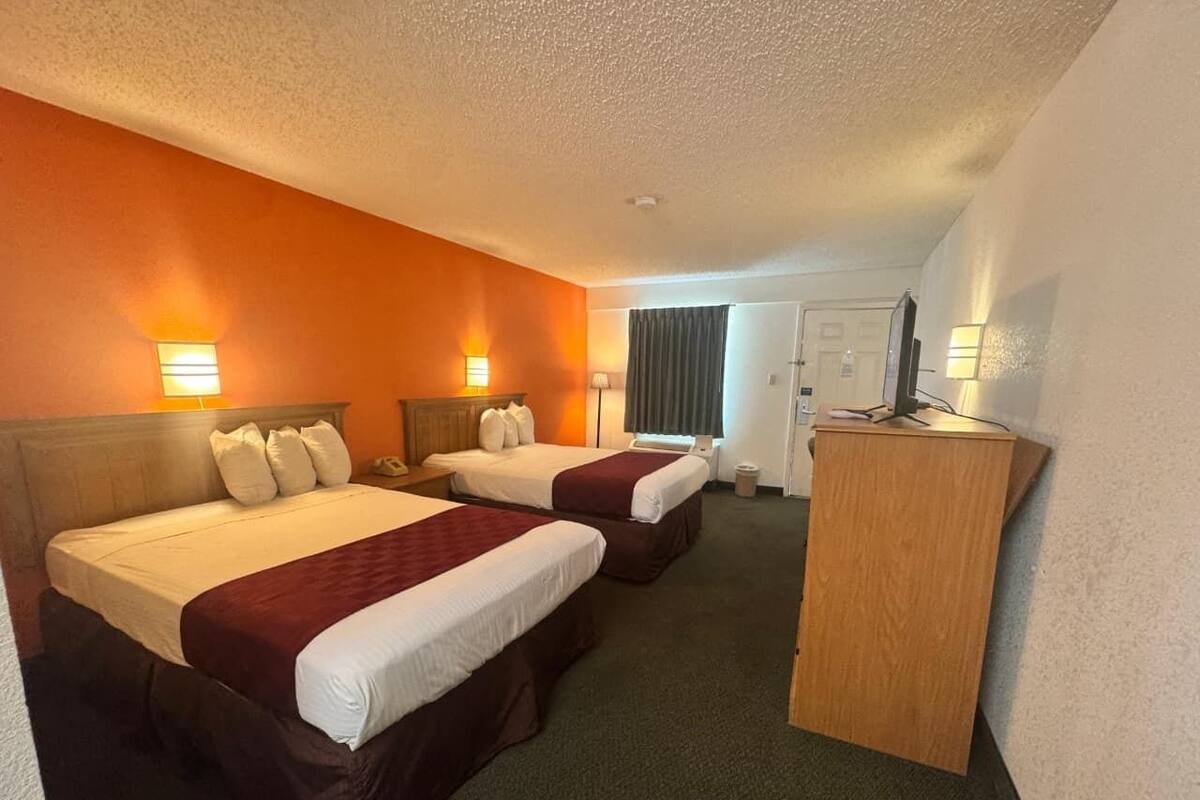 A hotel room with two beds, a desk, and a chair.