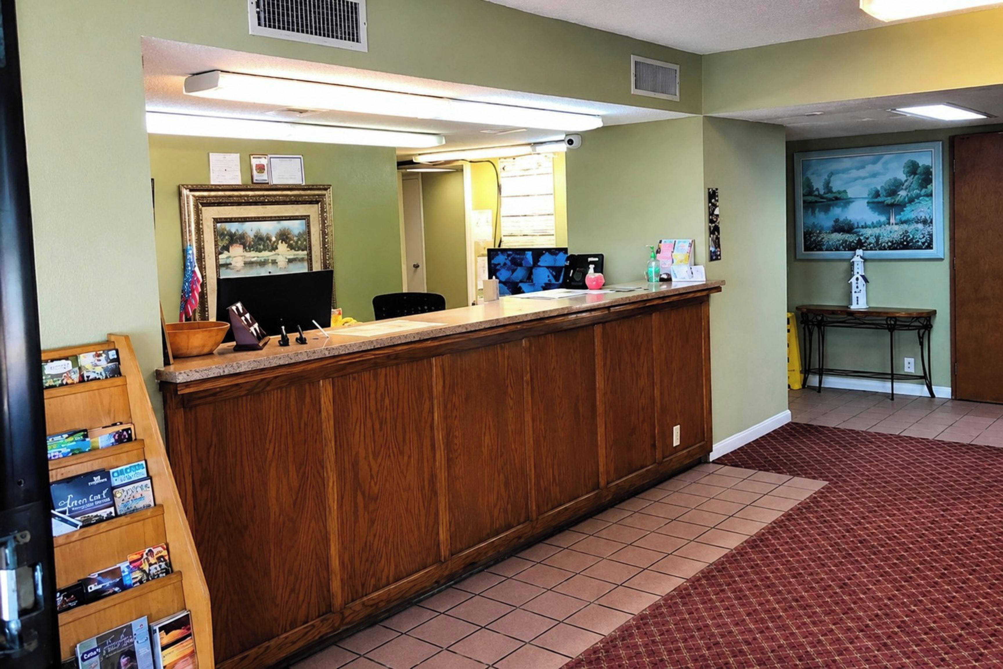 A reception desk with a wooden counter, a computer monitor, and various items on the desk.