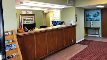 A reception desk with a wooden counter, a computer monitor, and various items on the desk.